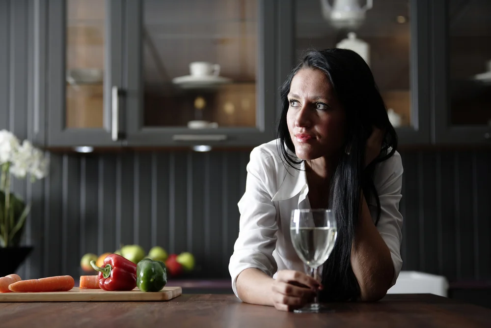 Attractive young woman enjoying a glass of wine in her kitchen.-1